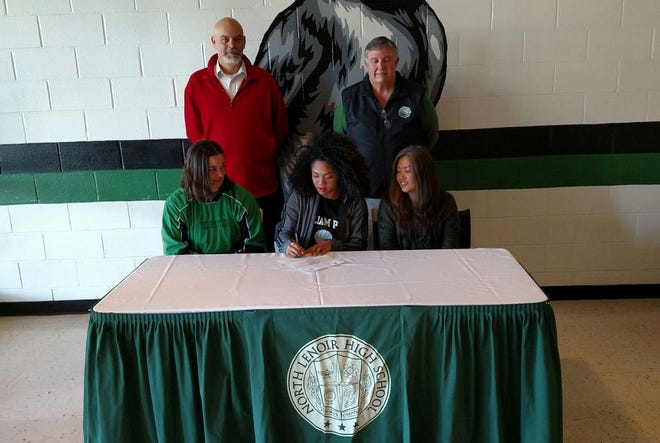 North Lenoir’s Mya Parks signs a document for William Peace University, seated next to Hawks volleyball coach Heather Carson, left, and her mother, Noriko Parks, Wednesday at North Lenoir High School. The school’s principal, Gil Respess, left and athletic director, Wayne Barwick, were also present.