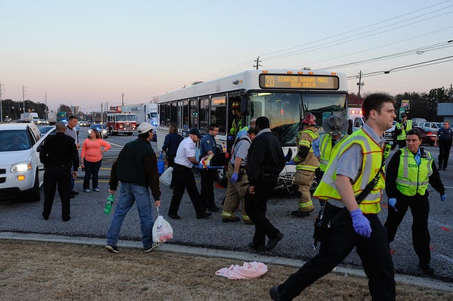 Officials move an injured bus passenger toward an ambulance on the scene of an accident involving a SUV and an Athens-Clarke County bus along Atlanta Highway near the Georgia Square Mall on Friday, Feb. 12, 2016. The SUV failed to yield to the bus while turning left. Twelve people were transported to the hospital from the scene. (AJ Reynolds/Staff, @ajreynoldsphoto)