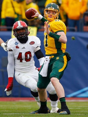 FILE - In this Jan. 9, 2016 file photo, North Dakota State quarterback Carson Wentz (11) passes as Jacksonville State defensive end Darius Jackson (40) applies pressure during NDSU’s 37-10 win in the FCS championship NCAA college football game, Saturday, Jan. 9, 2016, in in Frisco, Texas. North Dakota State football coaches enjoyed some free advertising on the recruiting trail of this year’s class. Wentz, NDSU’s standout quarterback, was fresh off a dramatic national championship victory and wowing Senior Bowl observers when the Bison staff was putting the finishing touches on more than two-dozen new recruits. (AP Photo/Mike Stone, File)