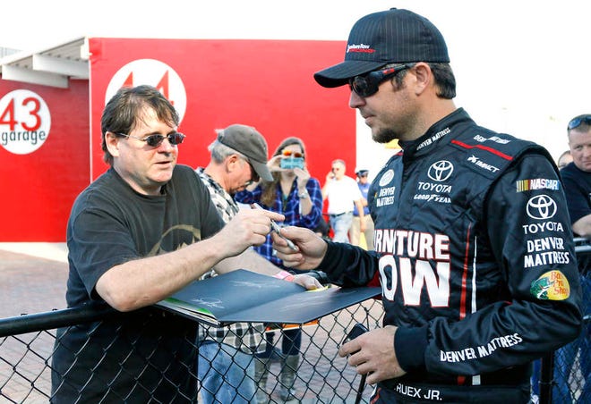 NASCAR driver Marin Truex Jr., right, signs autographs for fans before practice on Friday at Daytona International Speedway in Daytona Beach. (AP Photo/Terry Renna)