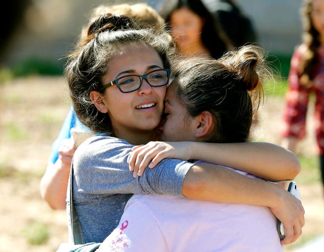 A mother and daughter reunite, Friday, Feb. 12, 2016, in Glendale, Ariz., after two students were shot and killed at Independence High School in the Phoenix suburb. The danger at the campus was over, police said, as worried parents crowded stores nearby to meet their children. (AP Photo/Matt York)