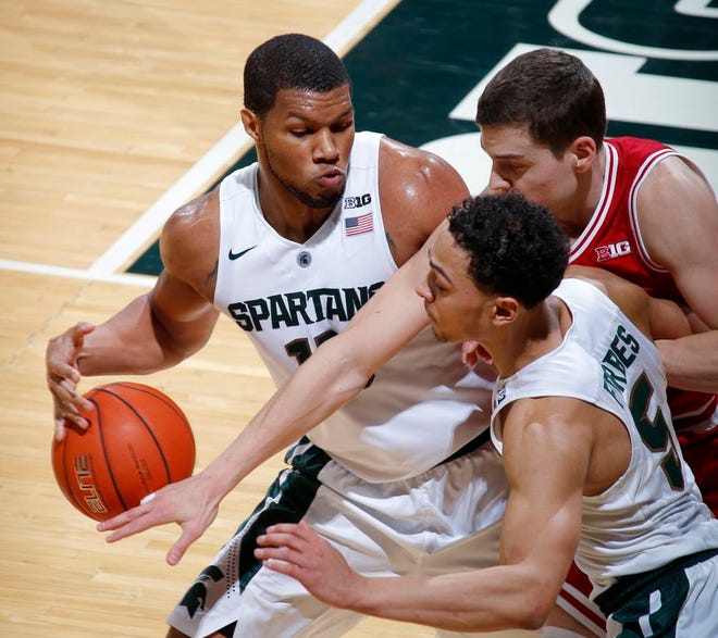 Indiana's Nick Zeisloft, right rear, reaches in to foul Michigan State's Marvin Clark Jr., left, as Michigan State's Bryn Forbes (5) watches during the first half of an NCAA college basketball game, Sunday, Feb. 14, 2016, in East Lansing, Mich. (AP Photo/Al Goldis)