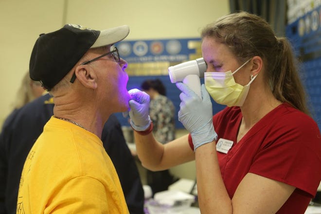 Emily Kohler checks for abnormal lesions in the soft tissue inside Robert Hoffman's mouth during the Veteran's Health Fair on Saturday in Panama City Beach.