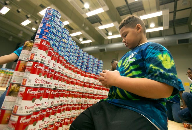 Roger Clay with Skyland Elementary School stacks cans of Campbell's soup to build an American Flag during the second annual Canstruction, Jr. Event held on Friday, Feb. 27, 2015 at Tuscaloosa Career & Technology Academy. Approximately 120 students from 12 different elementary and middle schools made up the twelve teams that designed and built giant structures made entirely out of full cans of food. At the end of the exhibitions, all of the food was donated to the West Alabama Food Bank. Last year the Tuscaloosa City Schools donated more than 5,000 cans of food through this event. staff photo | Robert Sutton