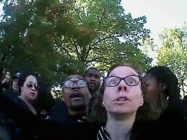 In an image taken from Columbia Police Department body camera footage, Jonathan Butler, center left, and Melissa Click confront an officer during the Concerned Student 1950 protest during the University of Missouri Homecoming parade last year.