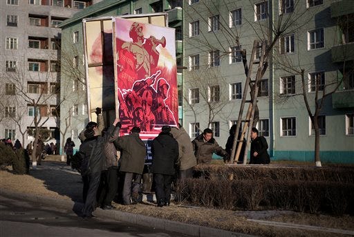 In this Sunday, Feb. 14, 2016 photo, North Korean men put up a propaganda poster urging its citizens to carry out their country's ruling party's goals for North Korea with an unwavering spirit in Pyongyang, North Korea. North Korea launched a rocket on Feb. 7, carrying what it said was an Earth observation satellite into space. The launch, which came about a month after the country's fourth nuclear test, was quickly condemned by outsiders as a test of banned ballistic missile technology. (AP Photo/Wong Maye-E)