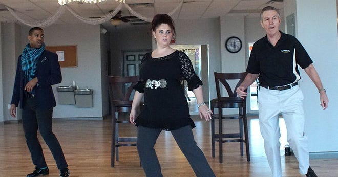 Choreographer Greg Mitchell, left, looks on while studio owner Amanda Deveau rehearses with Mike Clark for a charity "Dancing With the Stars" event.