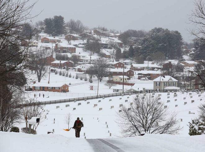 Scott Reed helps people on Preston Road in Vinton, Virginia, shovel with Mountain View Cemetery in the distance on Monday, Feb. 15, 2016.