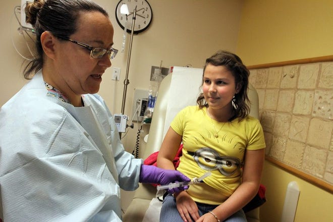 Gisela Carrier, 12, receives her weekly chemotherapy at the pediatric oncology clinic at Hasbro Children's Hospital, from her primary nurse, Angi Hastings.