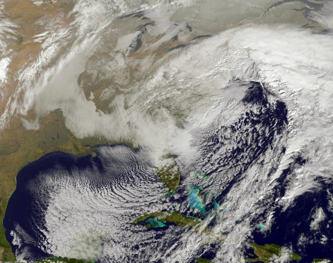 A weather satellite pierces the clouds of January's enormous winter storm to view millions of Americans rushing to buy bread, eggs and milk.