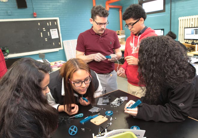 Tenth-graders Ana Familia, Jailin Mostafa, Naylib Batista (standing in red), and Destiny Delgado work with CTE teacher Alex Dornback as they work to assemble a starter robot kit at the Academy for Career Exploration in Providence. The Providence Journal/Sandor Bodo