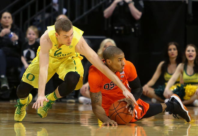 Oregon’s Casey Benson (left) and Oregon State’s Gary Payton dive for a loose ball in Saturday’s game. (Brian Davies/The Register-Guard)
