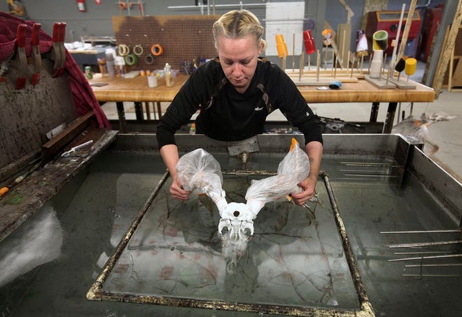 In this Feb. 10, 2016 photo, Andrea Elston, vice president of Color and Camo Graphics in Quincy, Ill., adds a camo pattern to a deer skull for a client. The company is using hydrographic dipping techniques to add camo and other patterns to a number of items including ATV hoods and outdoor gear. (Steve Bohnstedt)/The Quincy Herald-Whig via AP)
