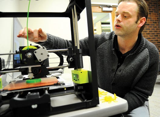 Pekin Public Library employee Nick Meskimen explains how the library's new 3-D printer operates Tuesday. The printer was recently purchased through grants received by the state and federal governments.