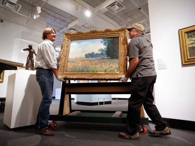 Chief preparator Michael Peyton, right, and preparator Tim Joiner, left, prepare to hang Claude Monet's "Champ d'avoine (Oat Field)," 1890, upon its return Tuesday to the Harn Museum of Art after being gone for eight months as part of the Harn's traveling exhibition, "Monet and American Impressionism."