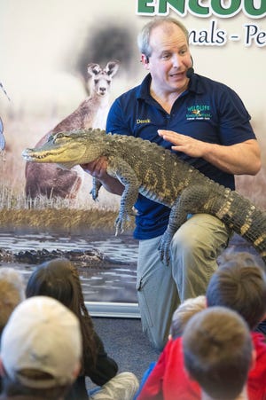 Derek Small shows holds an alligator at the Dover Public Library Friday during a visit by Wildlife Encounters. Photo by John Huff/Fosters.com
