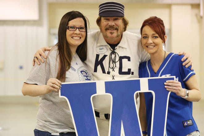 Nikiya Brummer and Amanda Link pose with Dave Webster, the guy who puts up the W after each Royals home win, during the World Series Trophy Tour stop at the Meadowlark Building on the Kansas State Fairgrounds Wednesday, Feb. 24, 2016.