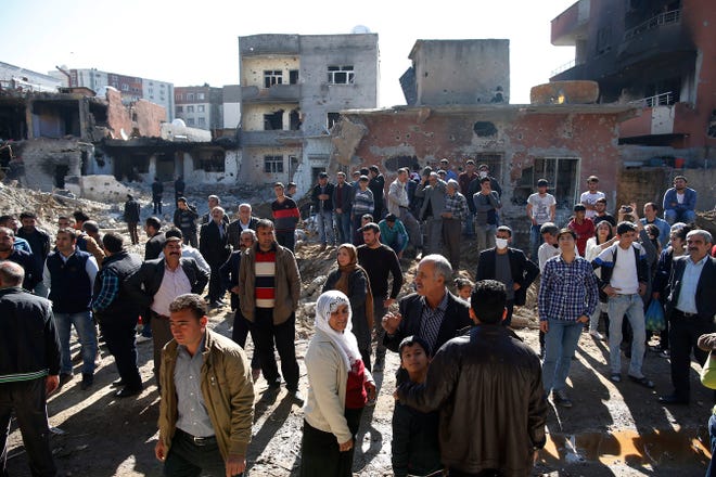 People look at ruined buildings in Cizre, Turkey, early Wednesday, March 2, 2016. Turkish authorities on Wednesday scaled down a 24-hour curfew imposed on the mainly Kurdish town of Cizre in southeast Turkey, nearly three weeks after declaring the successful conclusion of military operations there. The curfew was lifted at 5 a.m., allowing residents to return to their conflict-stricken neighborhoods for the first time since Dec. 14. But it will remain in effect between 7:30 p.m. and 5 a.m. Residents began trickling back at first light, their vehicles loaded with personal belongings and, in some cases, children. (AP Photo/Emrah Gurel)