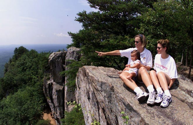 Lynn Cachione, left, points to a hawk flying by as she holds her daughter, Amelia, in her lap and takes in the view from atop Crowders Mountain with her friend, Besty Portnov, in this undated photo.