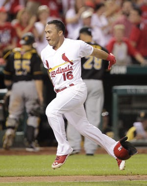 St. Louis Cardinals' Kolten Wong (16) tosses his helmet as he approaches home plate after hitting a walk-off home run, as Pittsburgh Pirates catcher Russell Martin (55) and relief pitcher Ernesto Frieri (29) head for the dugout in the ninth inning of a baseball game, Tuesday, July 8, 2014 in St. Louis. The Cardinals beat the Pirates 5-4. (AP Photo/Tom Gannam)