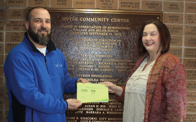 Doyle Community Center director Mike Liston recently presented $1,500 worth of Mom2Mom shopping vouchers to Laura Brott. Vouchers were made possible by the income generated from booth rentals fees for the seventh annual “Mega Mom2Mom Sale,” which is March 5.