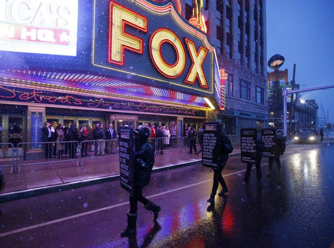 Protesters march in front of Detroit's Fox Theatre before Thursday night's Republican debate.