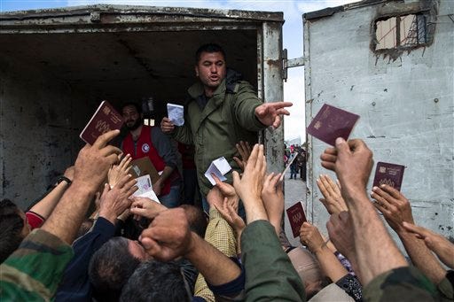 Turkmen people reach out showing their Syrian passports to receive humanitarian aid from the Syrian Arab Red Crescent in Al-Issawiyah, about 15 kilometers of Turkish border, Syria, Friday, March 4, 2016. Al-Issawiyah, populated by Turkmen, Turks' ethnic kin living in Syria, has remained peaceful unlike some other Turkmen areas at the border with Turkey where local militant groups opposed Syrian government forces.