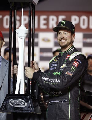 Kurt Busch holds up the trophy after winning the pole position for Sunday's NASCAR Sprint Cup Series auto race Friday, March 4, 2016, in Las Vegas. (AP Photo/John Locher)