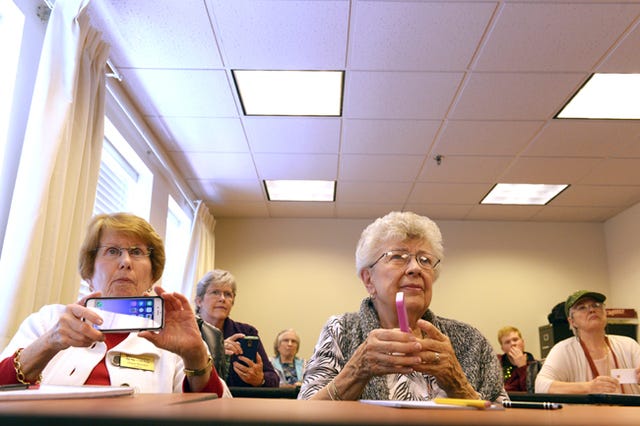 Residents at Westminster at Lake Ridge, a senior living community in Prince William County, Va., listen as Christian Magnuson, 16, teaches them to use their smartphones. Washington Post photo by Katherine Frey