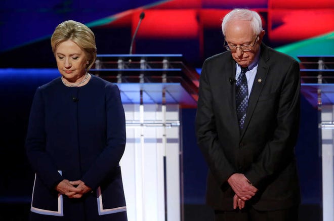 Democratic presidential candidates Hillary Clinton, left, and Sen. Bernie Sanders, I-Vt., stand on stage during a moment of silence for former first lady Nancy Reagan before a Democratic presidential primary debate at the University of Michigan-Flint on Sunday, March 6, 2016.
