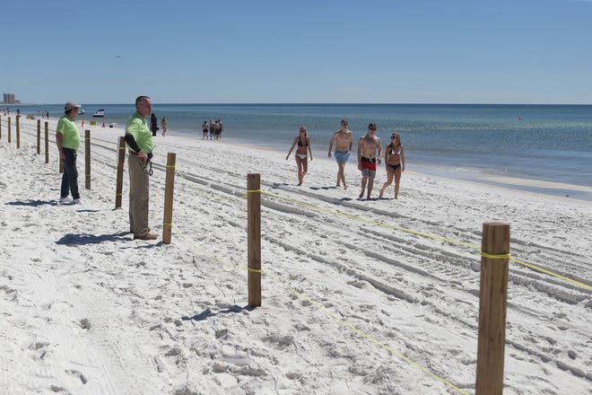 College students walk by a fenced outside Club La Vela on Panama City Beach on Sunday. Super-club owners say they have been unfairly targeted for erecting new fences that enclose most of the sand behind their establishments over Spring Break.