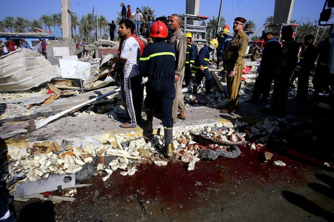 Civilians and security forces gather at the scene of a suicide bomb attack in Hillah, about 60 miles (95 kilometers) south of Baghdad, Iraq, Sunday, March 6, 2016. A suicide bomber on Sunday rammed his explosives-laden fuel truck into a security checkpoint south of Baghdad, killing and wounding dozens, officials said, the latest episode in an uptick in violence in the war-ravaged country. (AP Photo/Anmar Khalil)