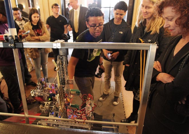 Mary Snapp, vice president at Microsoft Philanthropies, far right, gets a lesson in controlling a robot by Charlie Salgado, a ninth grader from Shea High School.
