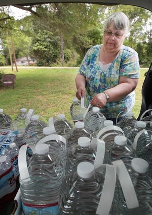 (Photo Mike Hensdill/The Gaston Gazette ) Patricia Holt unloads gallons of bottled water for her and her family as well as her chickens to drink at her home Thursday afternoon, May 7, 2015, on South Point Road.