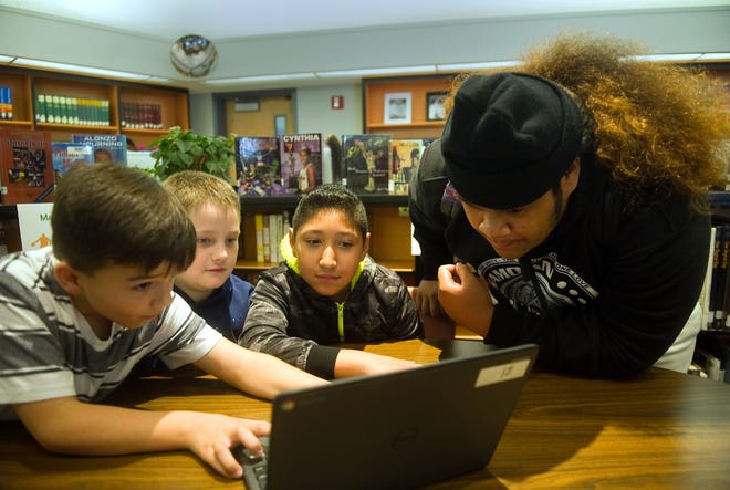 McCandless STEM Charter School students Eric Luman, left, Brian Clausan and Edgar Zatarain, all 9, show Lincoln High student Royal Sitigata a program they made that allows users to create interactive games and animations during a Teen Tech Week event Wednesday at the Lincoln High School library. CLIFFORD OTO/THE RECORD