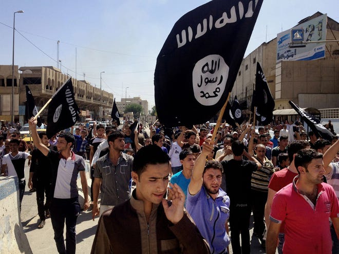 In this Monday, June 16, 2014 file photo, Demonstrators chant pro-al-Qaida-inspired Islamic State of Iraq and the Levant (ISIL) as they carry al-Qaida flags in front of the provincial government headquarters in Mosul.