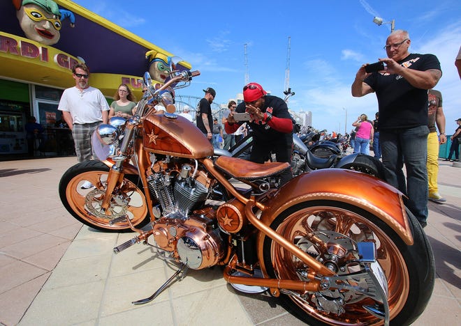 Those Mardi Gras looked just as amazed as admirers snapping photos of a copper motorcycle at the Boardwalk Classic Bike Show Friday in Daytona Beach. News-Journal/JIM TILLER