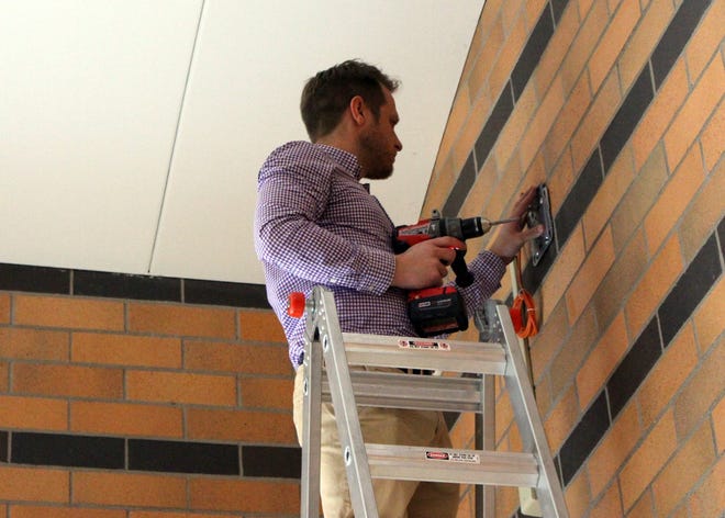 Aaron Wiggers, a systems engineer with Netech, a Presidio company, installs the mount for a wireless Internet access point on the wall near the cafeteria of West Ottawa High School's north building Wednesday, March 9, 2016. Amy Biolchini/Sentinel Staff