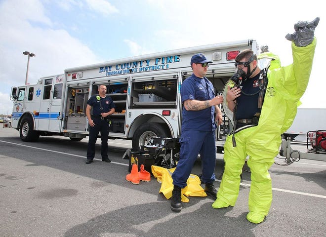 From left, Captain Tim Howard, Bay County Fire Rescue Hazmat Team Commander, looks on as U.S. Coast Guard Marine Science Tech Dillon Lyons helps Lt. Seth Imhof, with Bay County Fire Rescue, put on a level A hazmat suit in Panama City on Friday.