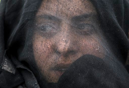 A woman shouts slogans during a protest by migrants demanding the opening of the border between Greece and Macedonia at the northern Greek border station of Idomeni, Sunday, March 12, 2016. Up to 14,000 people are stranded on the outskirts of the village of Idomeni in a makeshift camp.