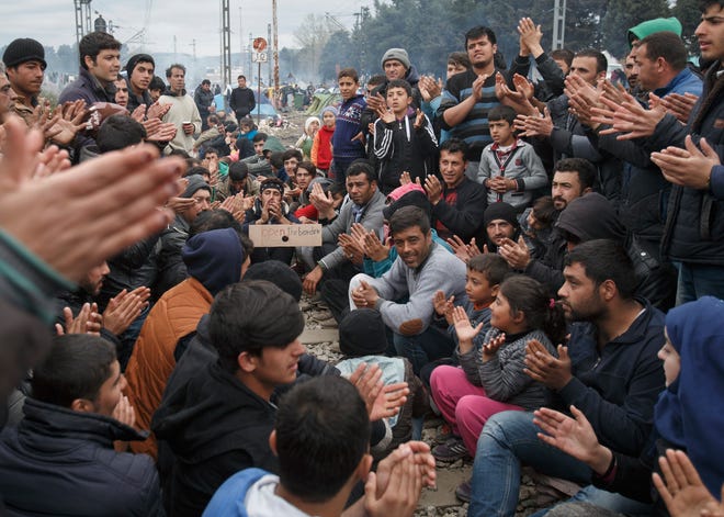 People clap during a protest by migrants demanding the opening of the border between Greece and Macedonia at the northern Greek border station of Idomeni, on Saturday. Up to 14,000 people are stranded on the outskirts of the village of Idomeni in a makeshift camp. VADIM GHIRDA/THE ASSOCIATED PRESS