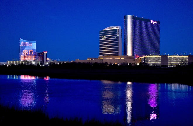 Water reflects the neon lights of the Borgata Casino and Spa and Harrah's Casino in Atlantic City at dusk, Tuesday, Feb. 2, 2016.