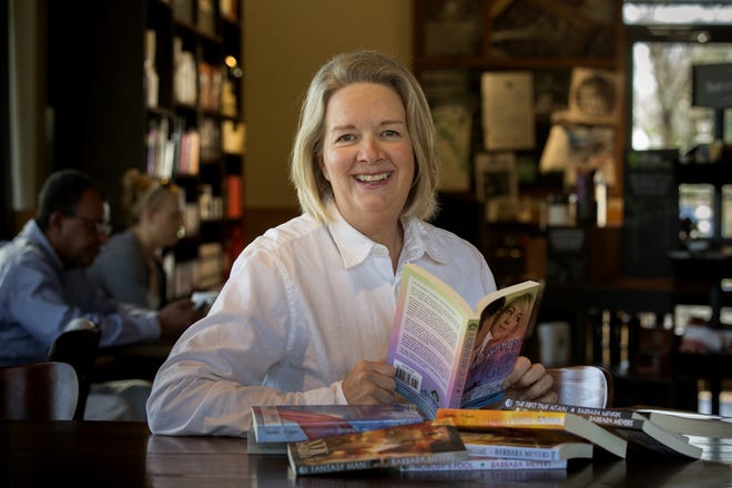 Barbara Meyers poses with some of the books she has written at the Starbucks where she works. Barbara works at Starbucks as a barista and is also an author, with several published books.