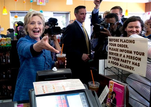 Democratic presidential candidate Hillary Clinton reaches to shake and employees hand behind the counter as she holds her iced tea during a visit to Dunkin' Donuts in West Palm Beach, Fla., Tuesday, March 15, 2016. Clinton faces Democratic rival Bernie Sanders in primary contests in five states on Tuesday: North Carolina, Florida, Ohio, Missouri and Illinois.