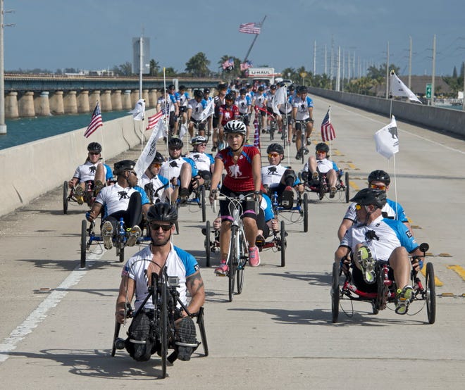 In this Jan. 10, 2014, photo provided by the Florida Keys News Bureau, wounded veterans of wars in Iraq and Afghanistan pedal their way across the Seven Mile Bridge in the Florida Keys near Marathon, Fla. The event was staged by the Wounded Warrior Project to help restore injured soldiers' physical and emotional well-being. (AP Photo/Florida Keys News Bureau, Andy Newman)