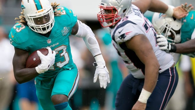 Miami Dolphins running back Jay Ajayi (23) looks for running room against the Patriots at Sun Life Stadium in Miami Gardens, Florida on January 3, 2016. (Allen Eyestone / The Palm Beach Post)