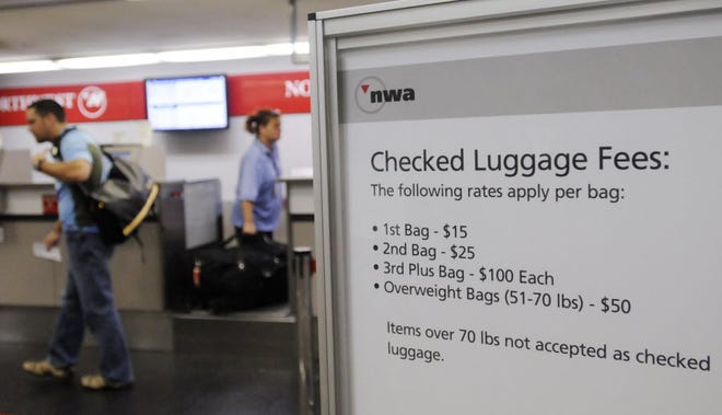 In this Sept. 10, 2008 file photo, a sign displays checked luggage fees at a Northwest Airlines ticket counter at MBS International Airport in Freeland, Mich.