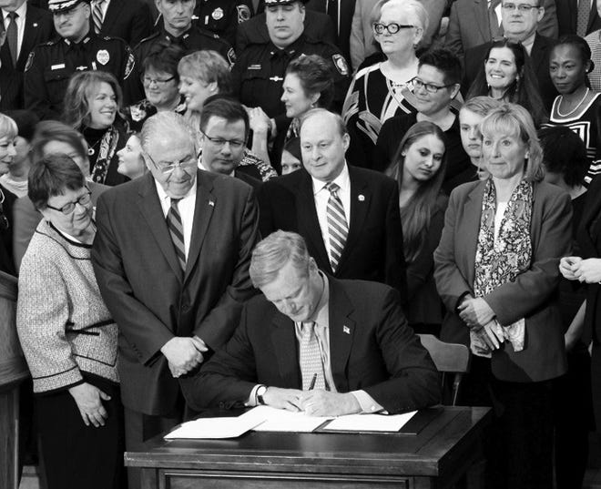 With legislative leaders looking on, Gov. Charlie Baker signs the substance abuse prevention bill into law during a Monday morning ceremony at the State House.