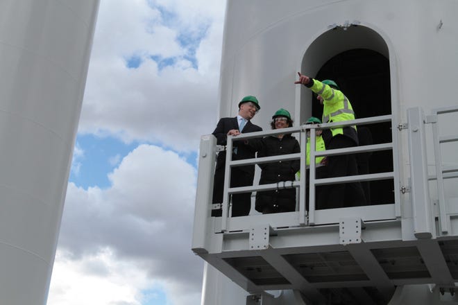 Jeff Grybowski, CEO of DeepWater Wind, left, and Governor Raimondo, center, tour a section of wind turbine tower at the Port of Providence on Friday. Project manager Eric Crucery is on the right. Workers are assembling the turbines for a wind farm off Block Island. The Providence Journal/Sandor Bodo