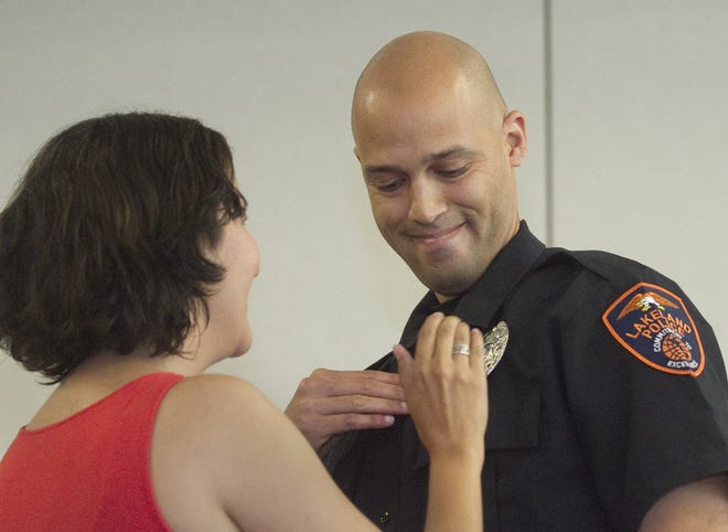 Lakeland Police Officer Daniel Lebreton, right, smiles proudly as his wife, Gloria Lebreton, pins his shield on his uniform during LPD's Promotion and Swearing In Ceremony at The First United Methodist Church in Lakeland on Friday. Thirteen new officers were sworn in and Officer Emma Molina was promoted to sergeant.
MICHAEL WILSON/THE LEDGER